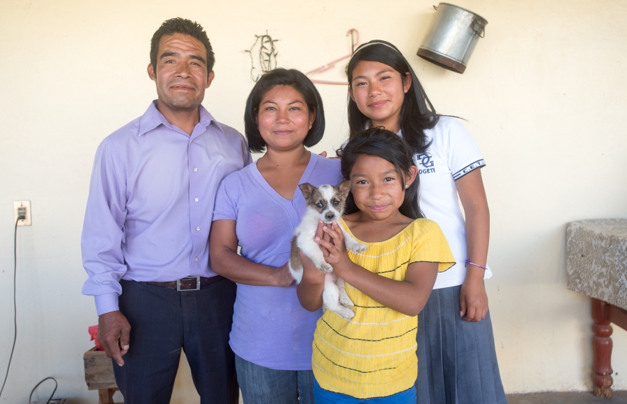 Family of four posed portrait, with youngest daughter in front holding a piuppy