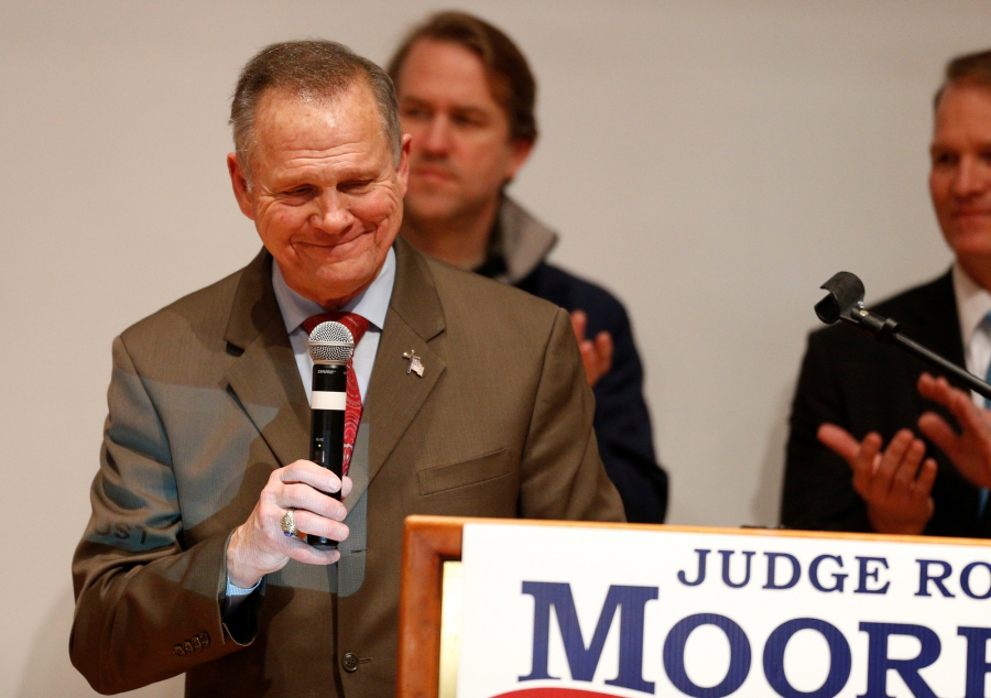 Republican US Senate candidate Roy Moore pauses as he addresses supporters at his election night party in Montgomery, Alabama, Dec. 12, 2017. Republican US Senate candidate Roy Moore stands with microphone in hand behind a placard of his campaign poster.