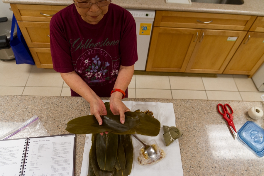 Woman holds bamboo leaves, ready to fold