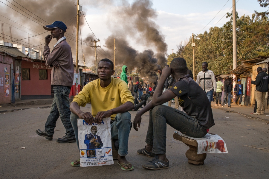 Men watch demonstrators light tires on fire in Nairobi’s informal settlement of Kaibera. The demonstration quickly turned violent as demonstrators armed themselves with stones and clubs bearing nails Wednesday evening. Men watch demonstrators light tires on fire in Nairobi’s informal settlement of Kaibera. The demonstration quickly turned violent as demonstrators armed themselves with stones and clubs bearing nails Wednesday evening.