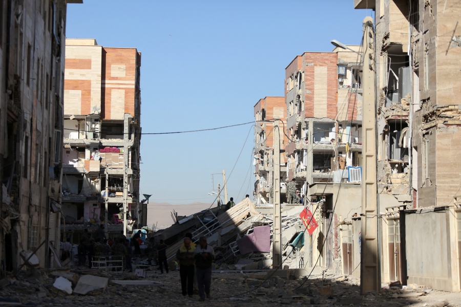 Damaged belongings are seen following an earthquake in Sarpol-e Zahab county in Kermanshah, Iran. Two men walk in the middle of a street with buildings on either side damaged.
