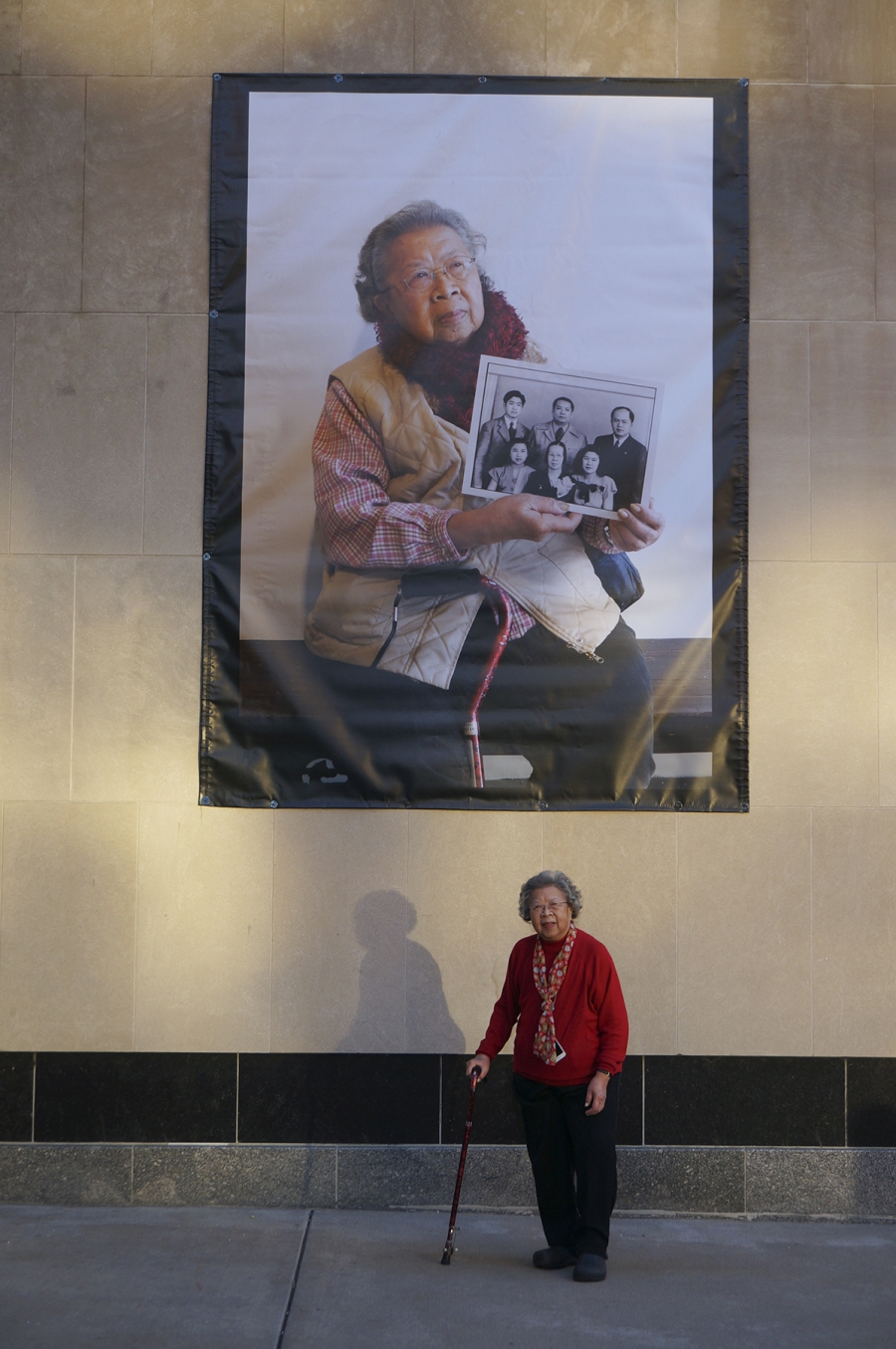 A woman stands in front of her portrait