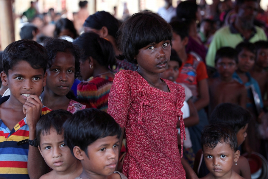 Rohingya refugees wait in a queue to collect food at the Palongkhali makeshift refugee camp in Cox's Bazar