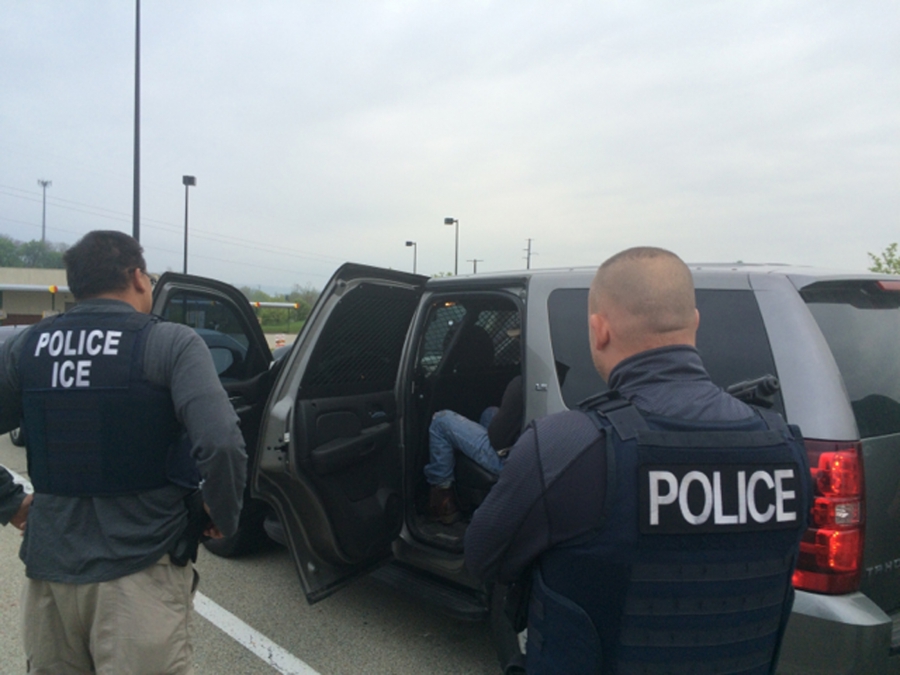 Agents with vests placing a man in car