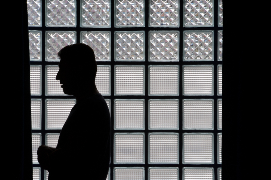A Muslim man is praying behind thick glass and heavy curtains at Al Taqua prayer space in the Metaxourgio neighborhood. A Muslim man is praying behind thick glass and heavy curtains at Al Taqua prayer space in the Metaxourgio neighborhood.
