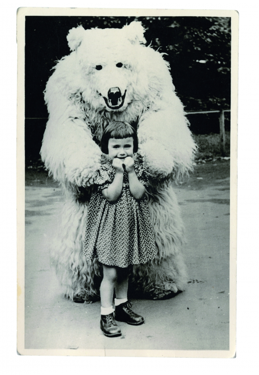 A young German girl stands with a man in a polar bear costume A young German girl stands with a man in a polar bear costume
