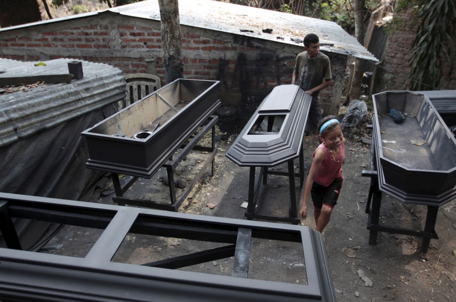 A worker applies sealant to a coffin at El Nuevo Renacer factory in Jucuapa. A worker applies sealant to a coffin at El Nuevo Renacer factory in Jucuapa.