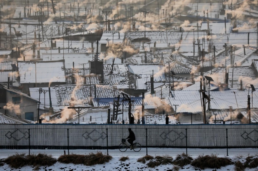 A North Korean man riding a bike is photographed from the Chinese side of the border