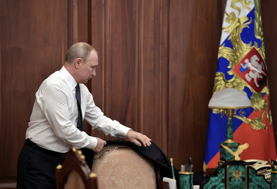 Russian President Vladimir Putin stands up from his desk and prepares to put on his suit jacket before his inauguration ceremony at the Kremlin in Moscow, Russia, May 7, 2018.