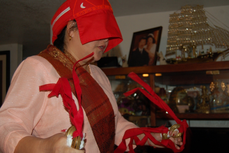 A Hmong shamans chants and rattles ceremonial bells at a healing ceremony.