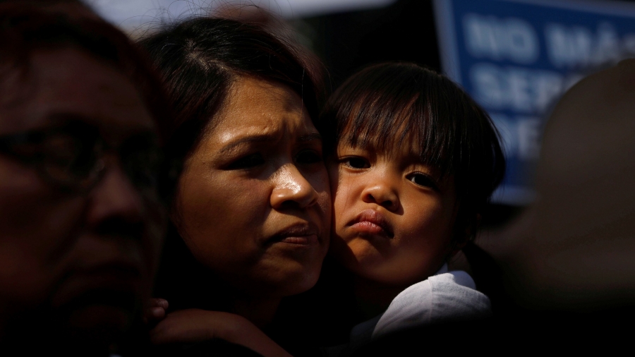 A child embraces a woman outside of City Hall in Los Angeles, California, on June 7, 2018 as people hold signs to protest against US policy to prosecute asylum seekers crossing the southern border and separate parents from their children. A mother is seen holding her child.