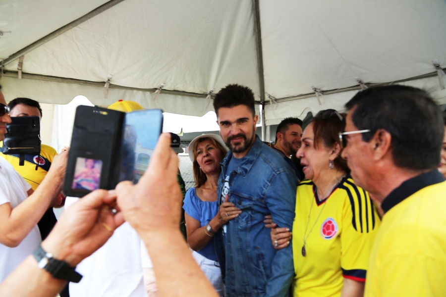 People take photos with there phones of man standing in middle of a crowd