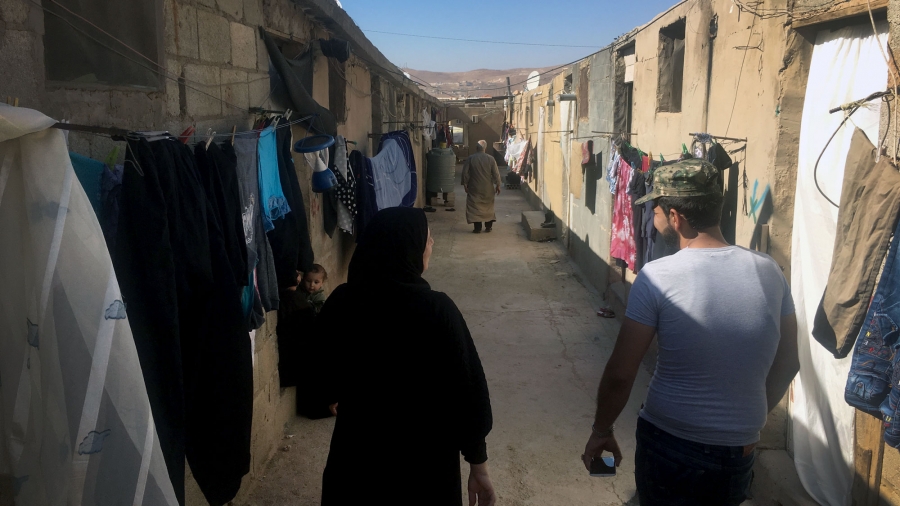 A man and a woman walk down a street lined with laundry