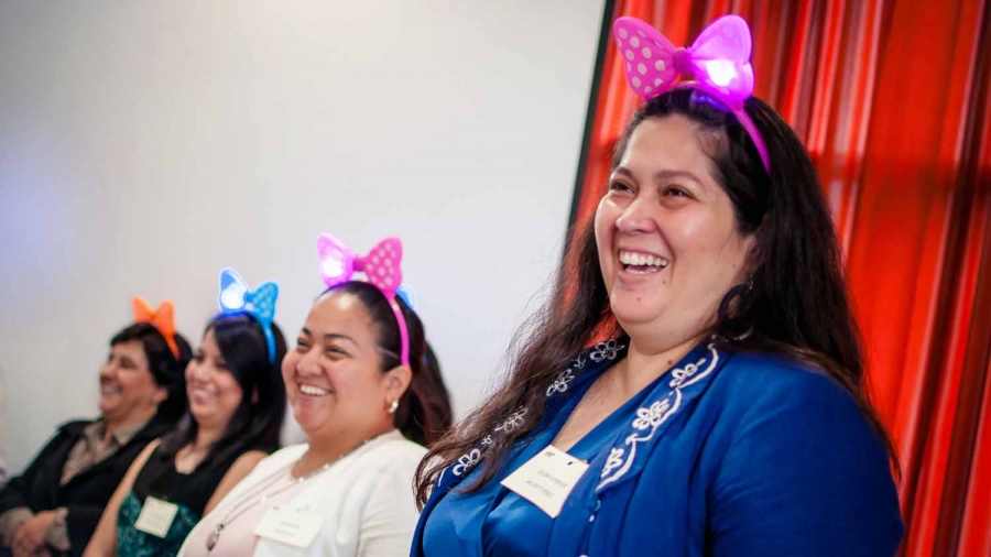 Four women wear light up headbands on their heads and are smiling.