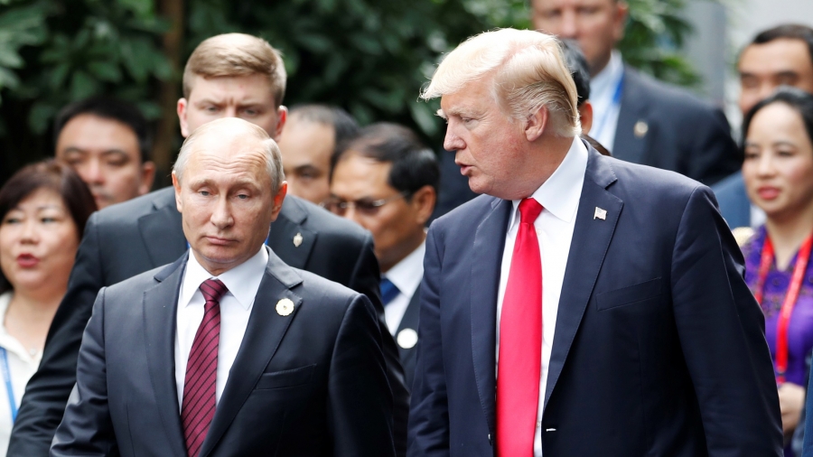 US President Donald Trump and Russian President Vladimir Putin talk during a summit in Vietnam, November 11, 2017. US President Donald Trump and Russian President Vladimir Putin are seen walking side-by-side surrounded by other officials.