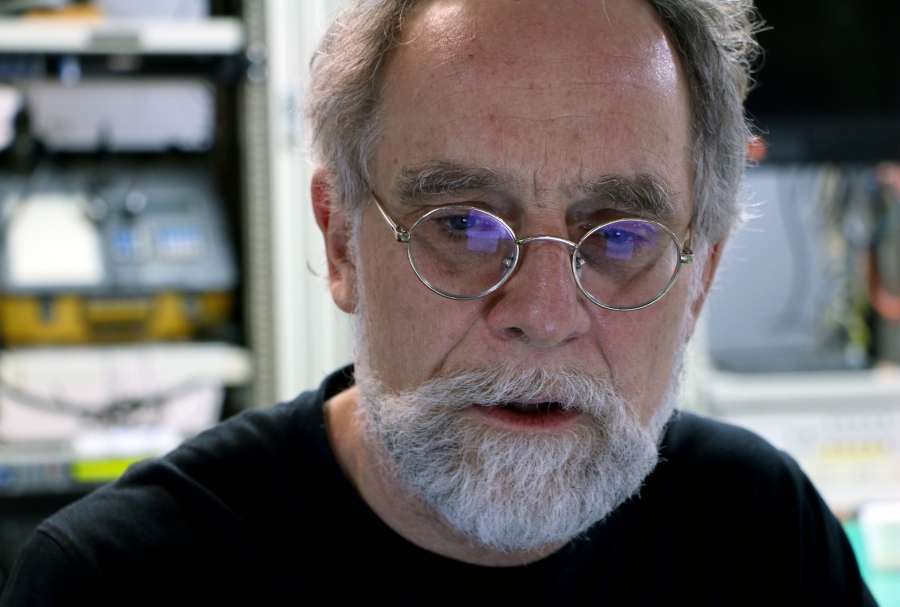 The blue light of a computer screen is reflected in a man's glasses.