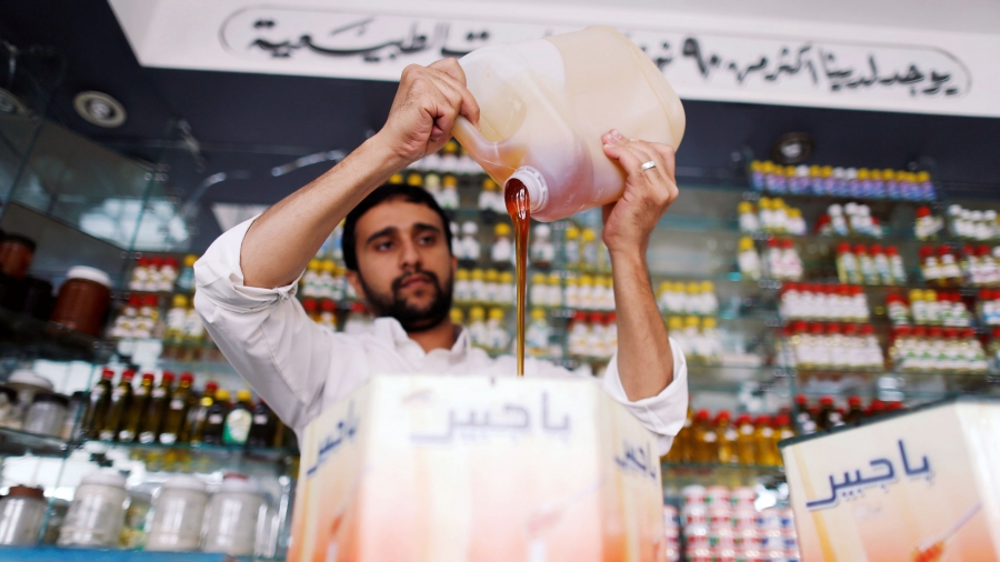 A man pours thick honey from a jug