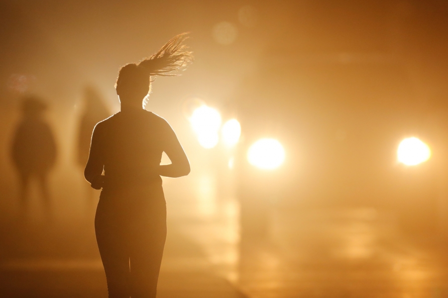 A women jogs along a roadside as temperatures cool off after sunset in Oceanside, California. A women jogs along a roadside as temperatures cool off after sunset in Oceanside, California.