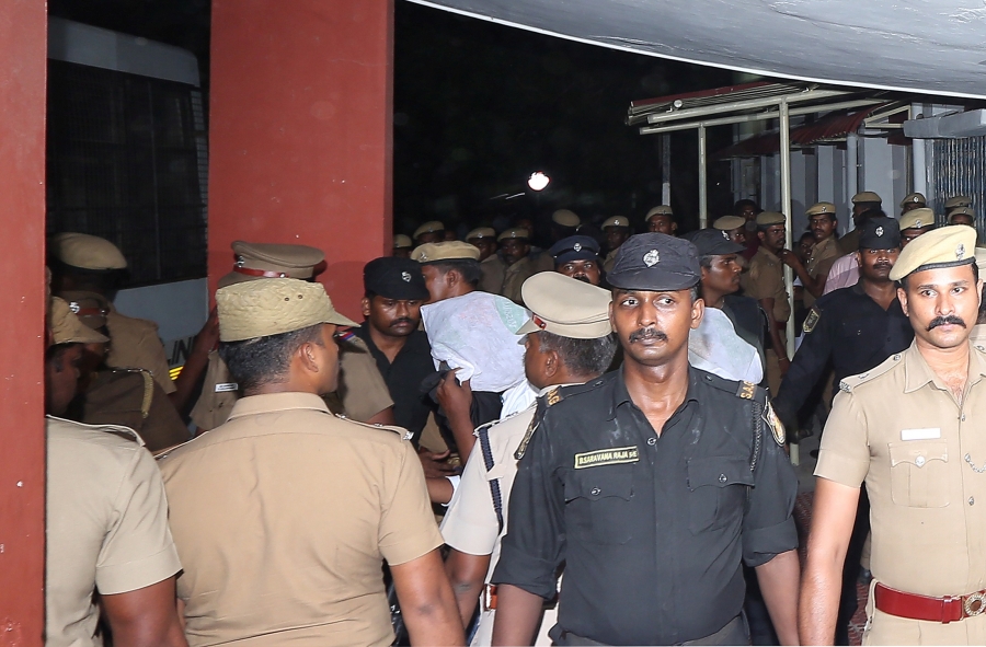 police huddled around a man with a covered face