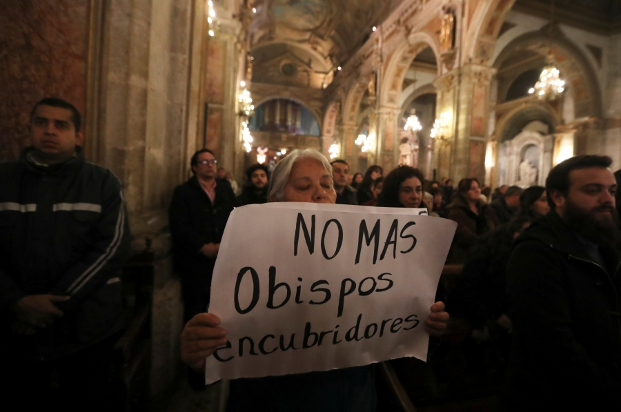 A woman holds a banner that reads, "No more bishops covering up"