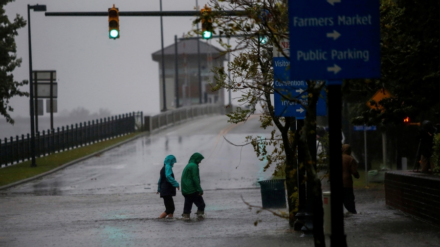 People walk on a local street as water from Neuse River starts flooding houses upon Hurricane Florence coming ashore in New Bern, North Carolina, Sept. 13, 2018. People are shown in rain jackets wading through a flooded street in New Bern, North Carolina, Sept. 13, 2018.