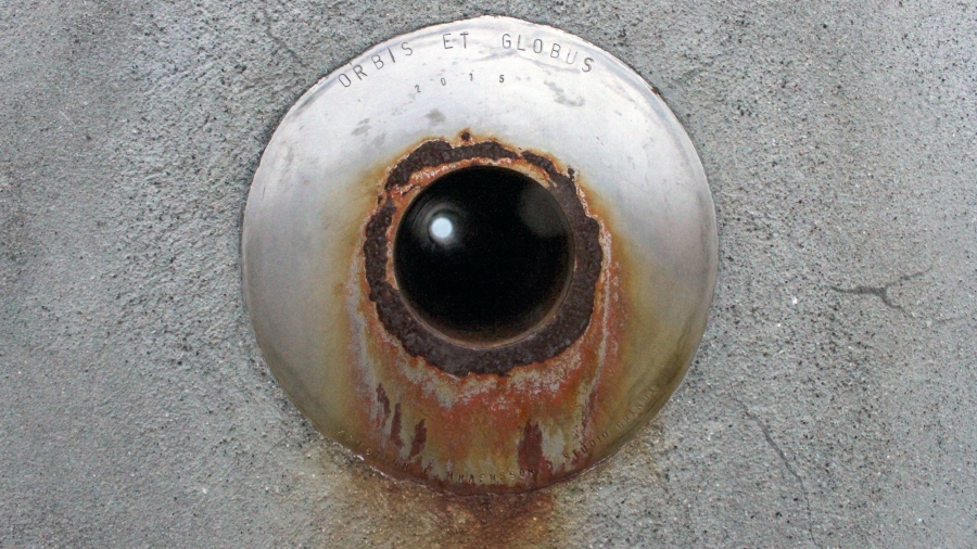 An inscription at the center of a monument in the shape of a grey concrete sphere