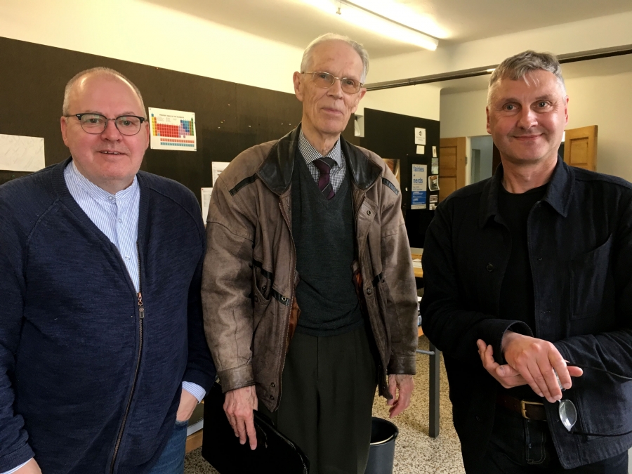 Three men stand shoulder to shoulder for a photo