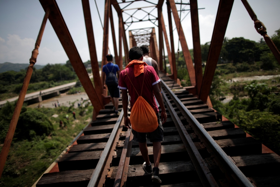 Migrants, part of a caravan of thousands from Central America en route to the US, walk on the train tracks, in Arriaga, Mexico Oct. 26, 2018. Migrants are shown walking along train tracks with their backs to the camera in Arriaga, Mexico Oct. 26, 2018.
