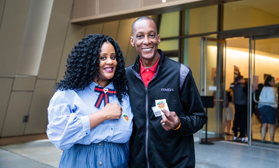 A woman and a man pose for a photo and display their "I voted" stickers.