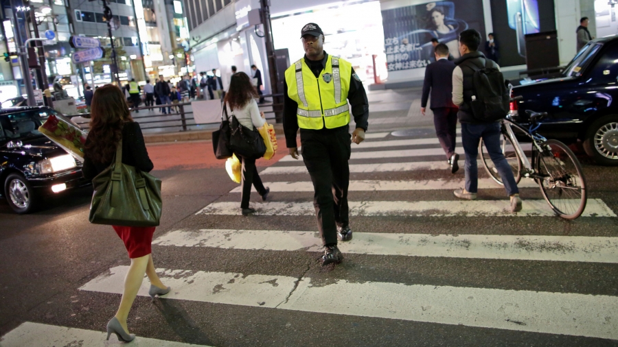 Japanese security firm Executive Protection Inc. employee, 59-year-old Antonio Nathaniel King of the US, patrols on the street at Roppongi shopping and amusement district in Tokyo, Japan, Nov. 1, 2018. Antonio Nathaniel King, from the US, is shown wearing his security uniform walking across a street in Tokyo.