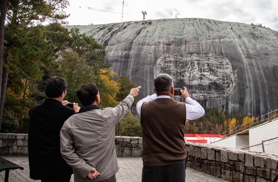 Tourists from Japan observe Stone Mountain. Tourists from Japan point at and take cell phone photos of Stone Mountain.