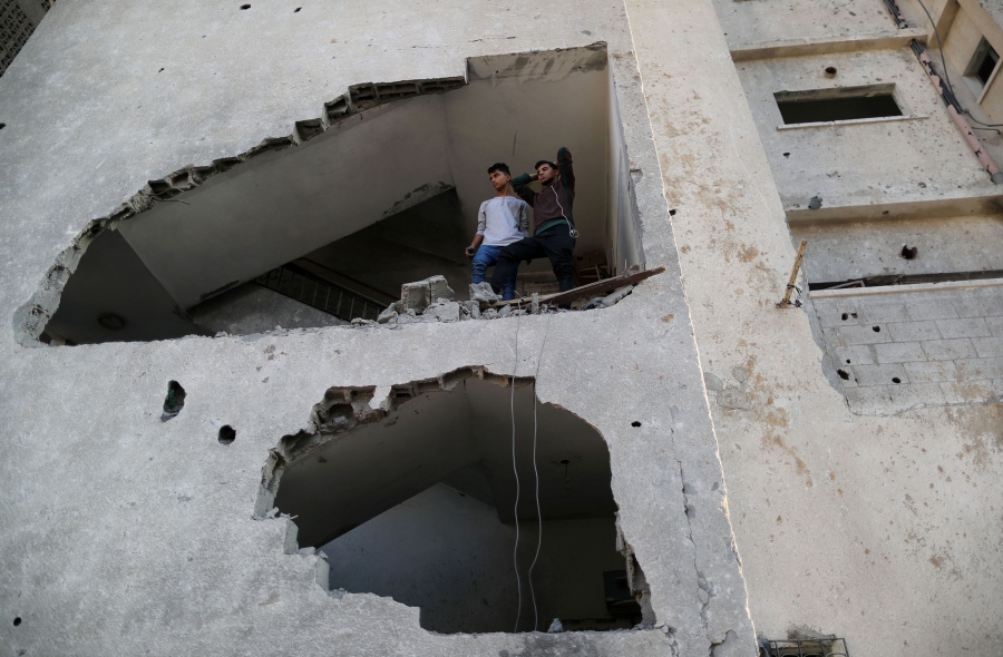 Palestinians look out of their house that was damaged in an Israeli air strike, in Gaza City, Nov. 13, 2018. Palestinians look out of their house through a large hole in the wall created from an Israeli air strike.