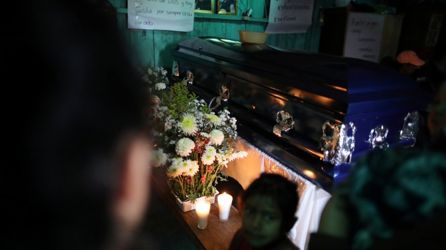 The coffin of Misael Paiz, 25, lies inside his family home before his funeral in Aguacate, Huehuetenango, Guatemala, Oct. 29, 2018. A blue coffin with flowers inside a home in Guatemala.