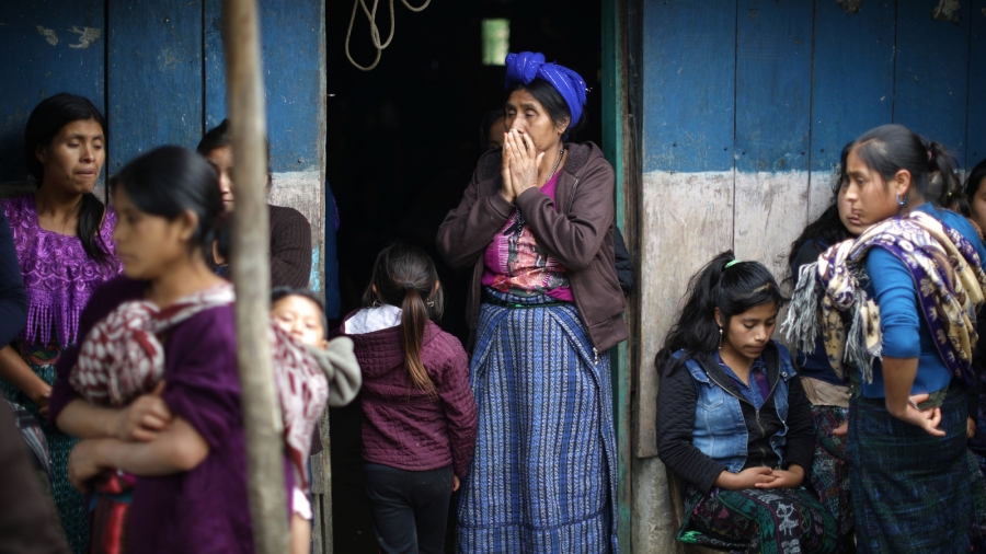 A woman stands in the doorway of the family home of Misael Paiz, 25, before his funeral in Aguacate, Huehuetenango, Guatemala, Oct. 29, 2018. A woman stands in the doorway, covers her hand in shock.