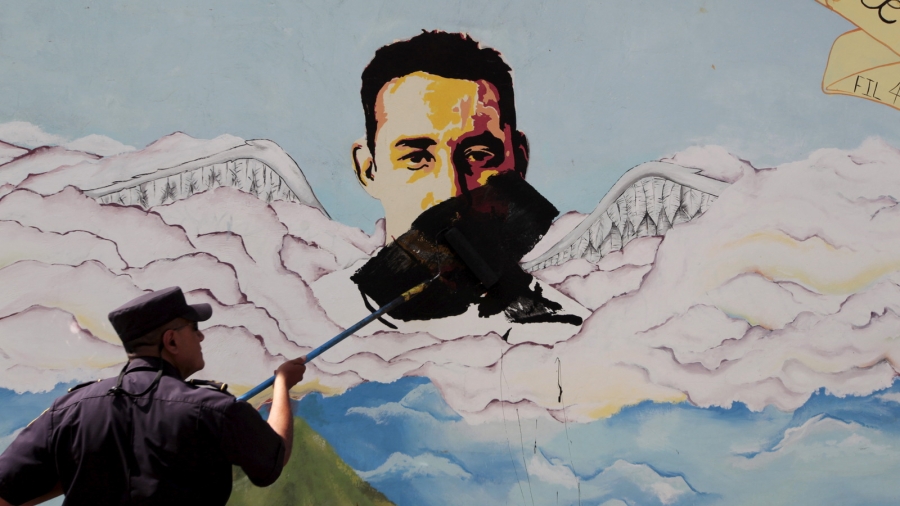 A police officer paints over a graffiti associated with the Mara Salvatrucha gang in the Montreal neighborhood in Mejicanos, El Salvador, Dec. 9, 2015. A man paints over graffiti of a face associated with a gang.