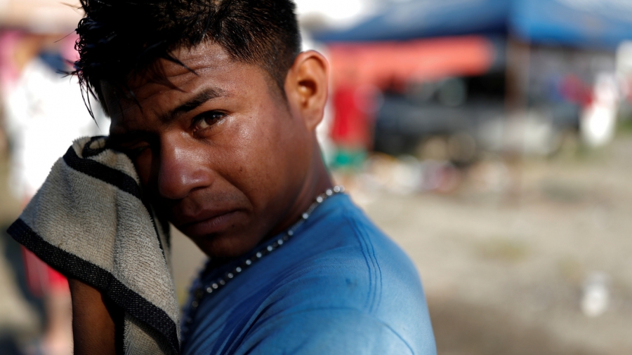 Edwin Sanchez, 19, a migrant from Honduras, traveling with a large group of migrants to the US. takes a moment to wash his face in Huixtla, Mexico, Nov. 1, 2018. A young man washes his face with a washcloth.
