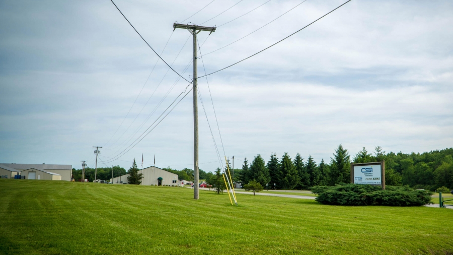 A sign says CSI on the side of the road with a long green lawn