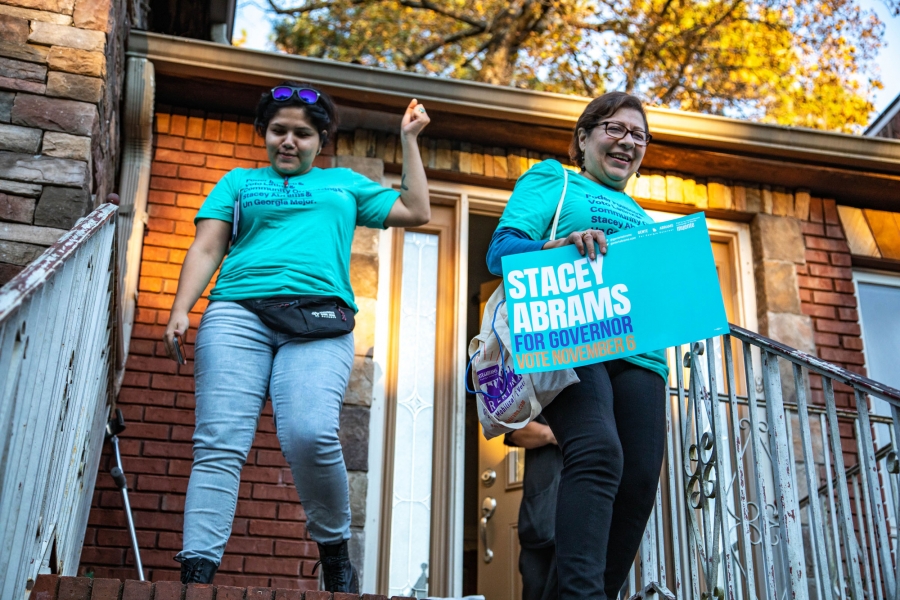 Gina Perez, of Gente4Abrams, has been going door-to-door in Gwinnett County, Georgia, in support of Democracy Stacey Abrams. Gina Perez and her colleague wearing light blue t-shirts supporting Democrat Stacey Abrams, walk door stairs.