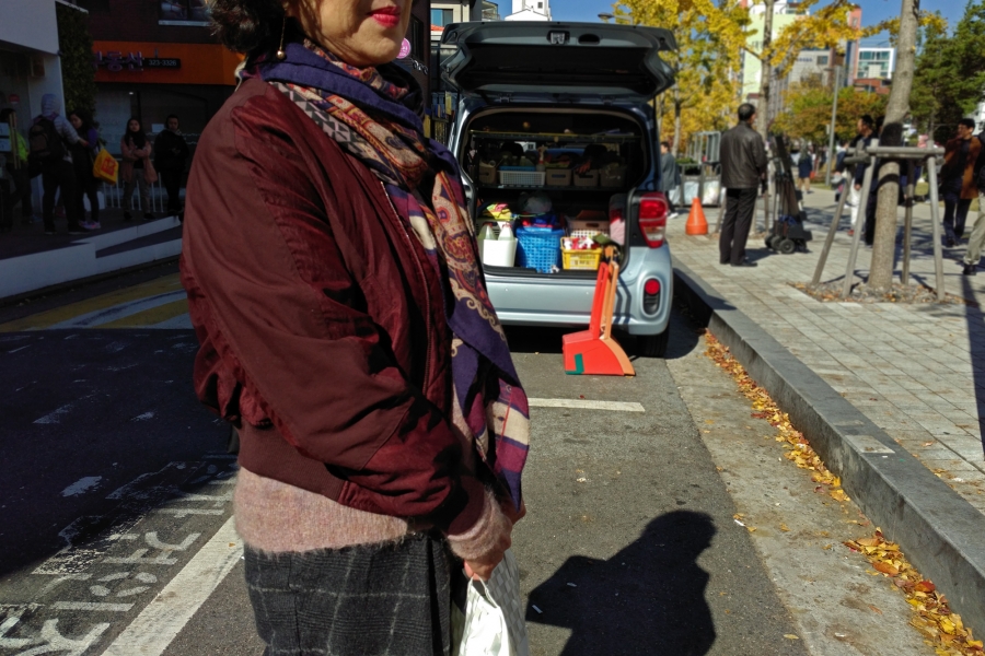 Hong Jung-hee, 68, from Daegu, South Korea. Hong Jung-hee, 68, wears a maroon coat and stands in the street.