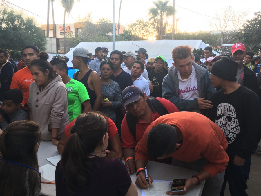 Dozens of migrants wait in line to talk to three attorneys from New York University.