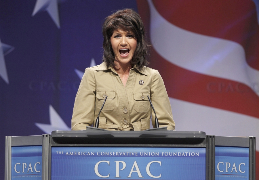 US Representative Kristi Noem stands at a podium with an American flag background