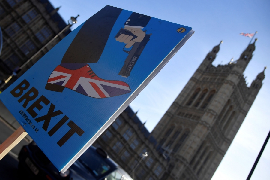 A demonstrator holds a placard during an anti-Brexit protest opposite the Houses of Parliament in London, Britain. A demonstrator holds a placard showing a Union Jack on a shoe with a gun pointed at the toe, during an anti-Brexit protest opposite the Houses of Parliament in London, Britain.