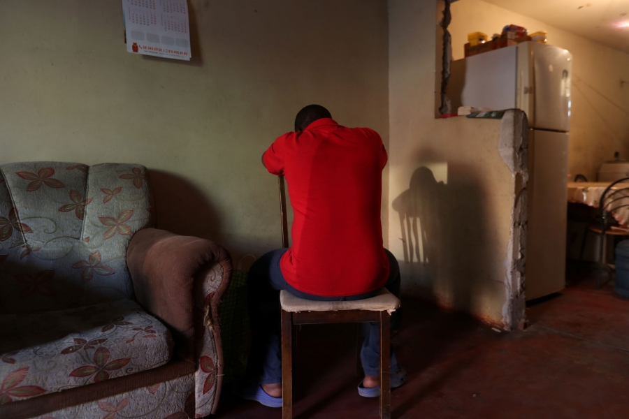 Haitian migrant Stephane, 19, hides his face as he poses for a photograph. Haitian migrant Stephane who is shown wearing a red shirt, hides his face as he poses for a photograph.