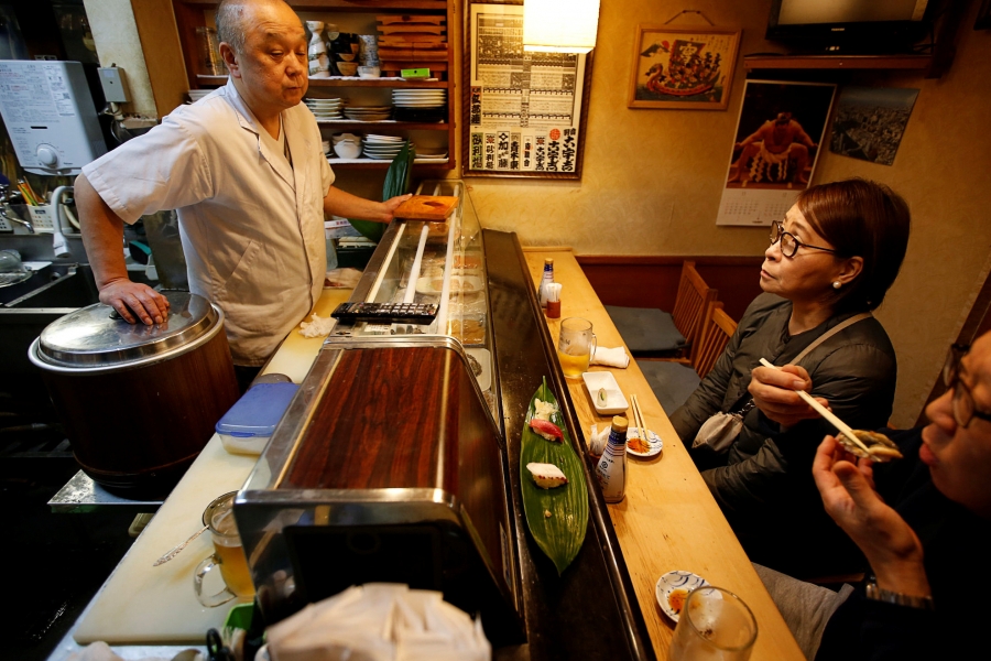 Masatoshi Fukutsuna, chef and owner of sushi restaurant Eiraku, chats with customers at his restaurant in Tokyo, Japan, Dec. 7, 2018. Chef chats with customers at sushi bar.