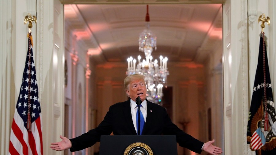 President Donald Trump addresses a news conference following Tuesday's midterm congressional elections at the White House. Donald Trump speaks at podium flanked by two flags.
