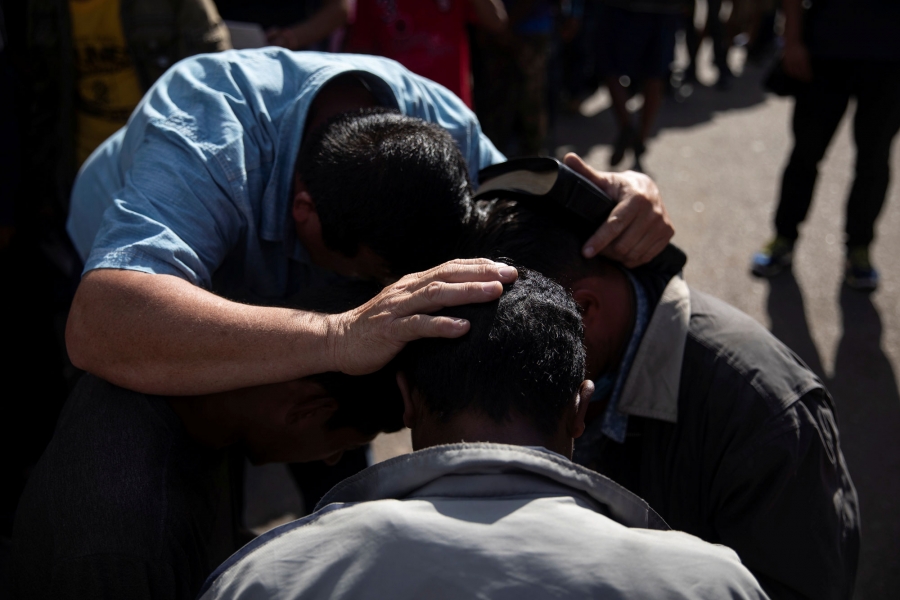 Pastor Jose Murcia preaches. Pastor Jose Murcia is shown with his hands on two people's heads preaching.