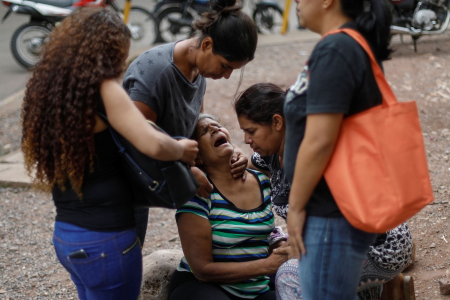 A woman reacts near the coffin of a man, who, according to the police, was kidnapped and killed, outside a morgue. A woman is shown weeping surrounded by four other women near the coffin.