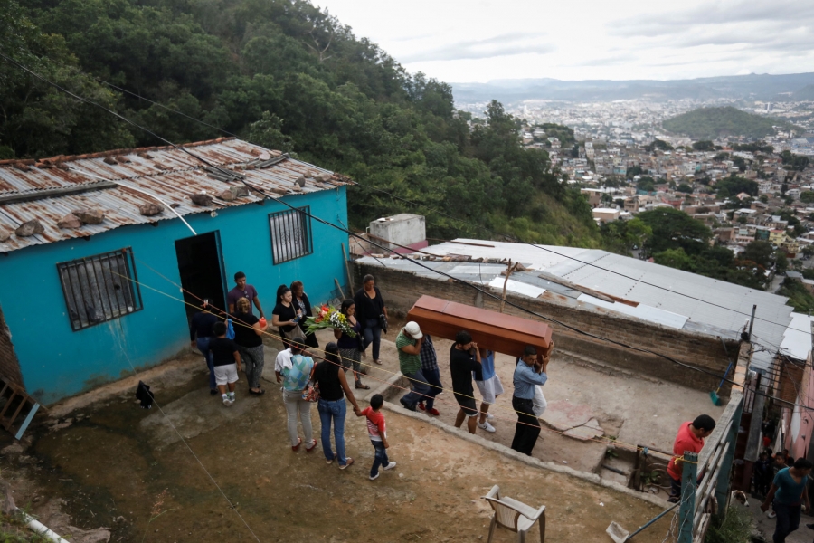 Relatives and friends of Ronald Blanco carry the coffin during his funeral. Relatives and friends of Ronald Blanco are shown walking out of a blue house on a hill overlooking Tegucigalpa, carrying his coffin.