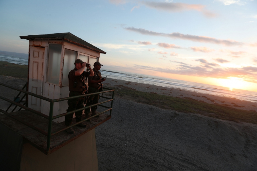 Policemen look out from a watchtower at the Chilean and Peruvian border. Two policemen look out from a watchtower — one looking through binoculars — at the Chilean and Peruvian border.