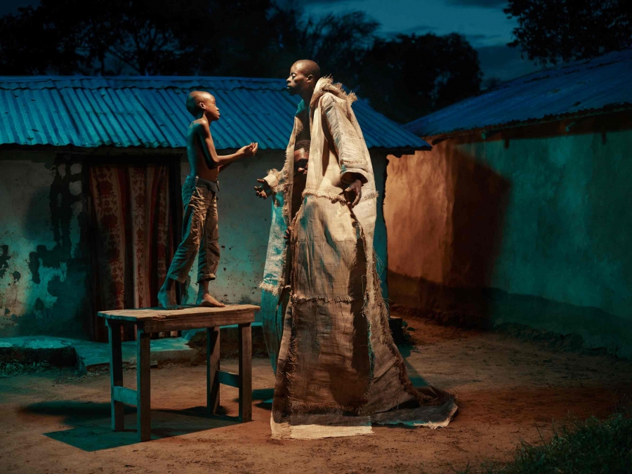 A small boy faces a man in a tall robe